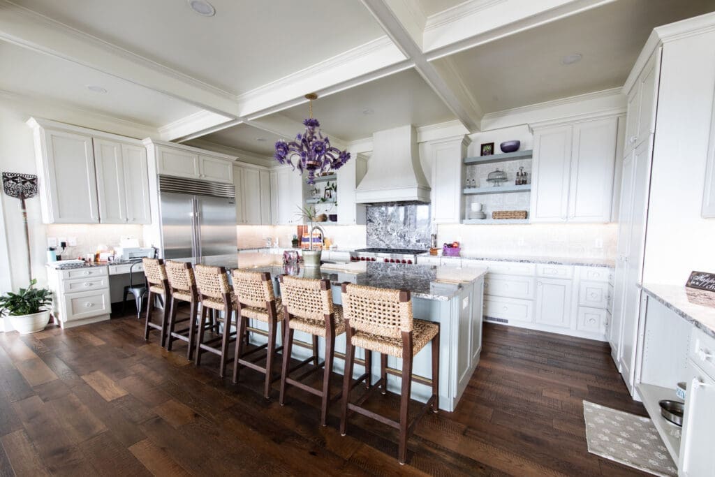 Bright modern kitchen remodel by JG Carpentry in Rapid City, SD featuring white cabinetry, granite countertops, hardwood flooring, and a large center island.
