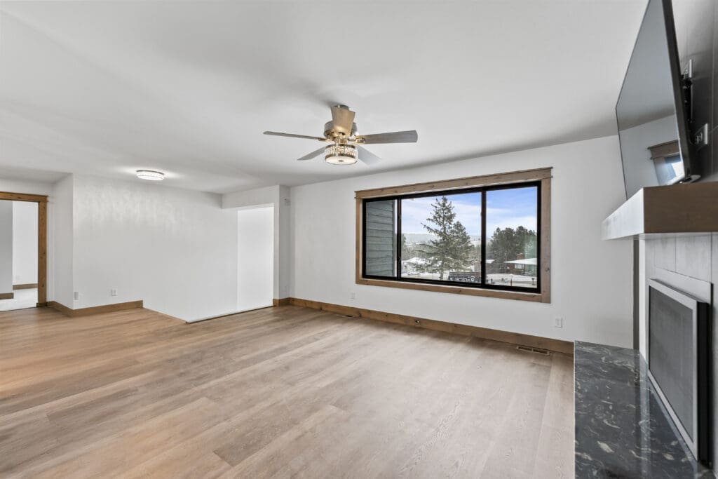 Completed full-home remodel in Spearfish, SD by JG Carpentry featuring updated hardwood flooring, modern fireplace, large picture window, and custom wood trim work.