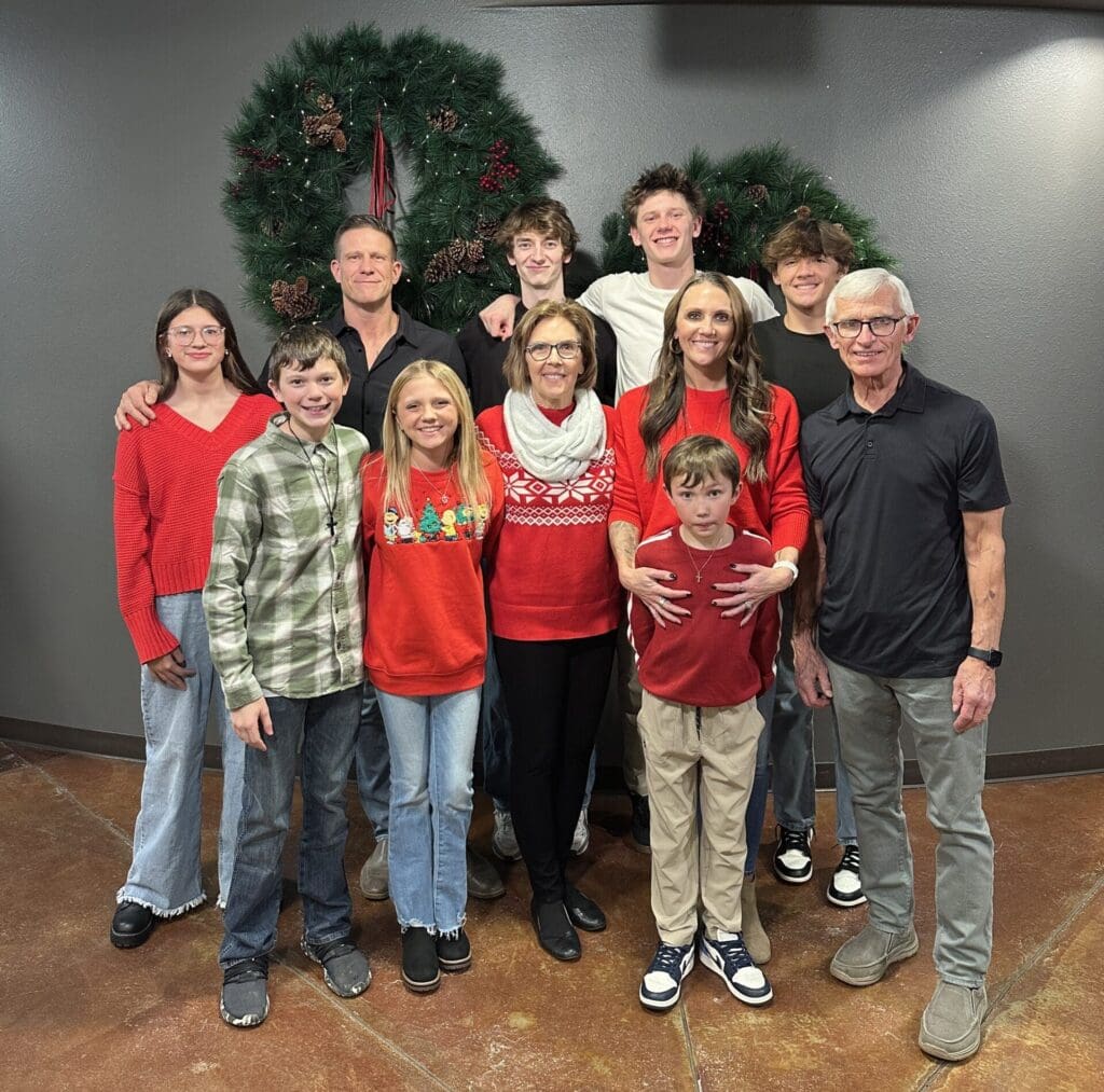 Jamie Gibbs, owner of JG Carpentry in Spearfish, SD, with his family posing together in front of large holiday wreaths.