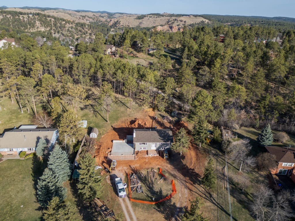 Aerial view of residential home addition project in Spearfish, SD by JG Carpentry showing excavation and site preparation in the Black Hills.